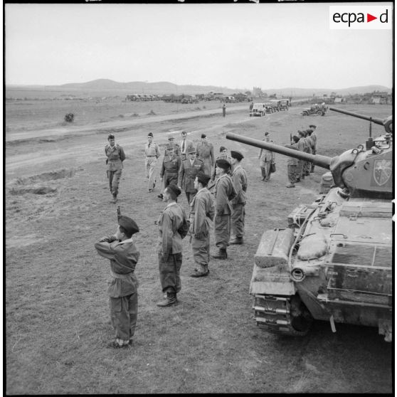 Le général de Lattre de Tassigny, en compagnie d'autres officiers, passe des troupes en revue devant un char Chaffee.