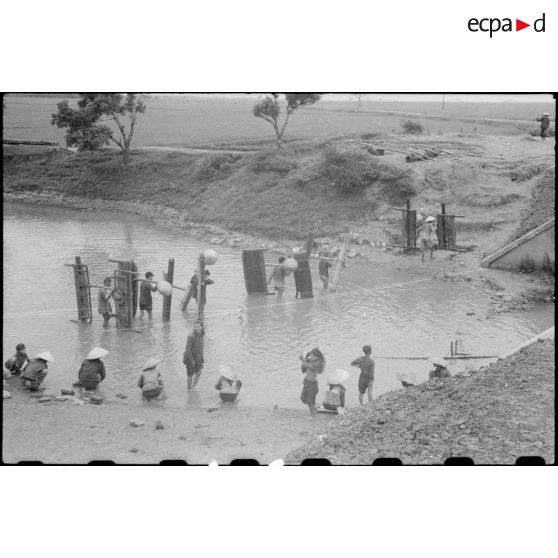 Des villageois participant aux travaux du poste de Trung Xa rejoignent leur village, tranportant du bois (peut-être des palissades).