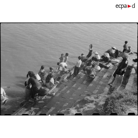 Des femmes et enfants vietnamiens font leurs ablutions sur les rives du fleuve à Nam DInh.