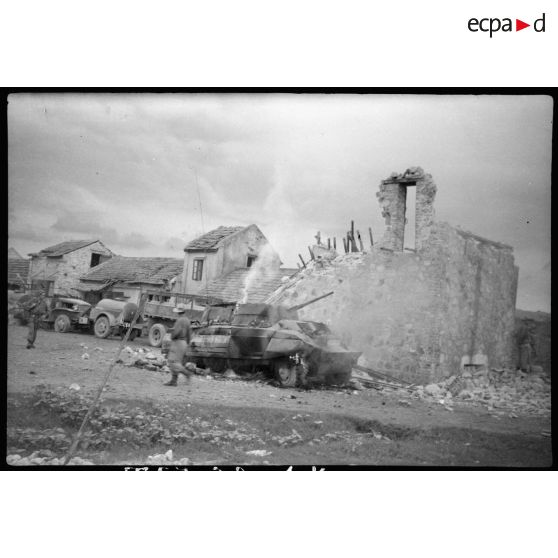A Mao Khe : des maisons partiellement détruites. Devant les bâtiments en ruine, une automitrailleuse et des GMC 6X6.