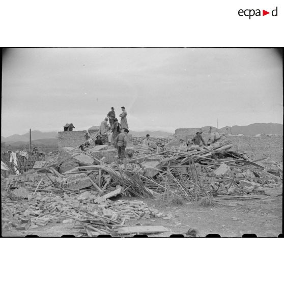 Des soldats fouillent les décombres d'un poste en ruines au Tonkin.