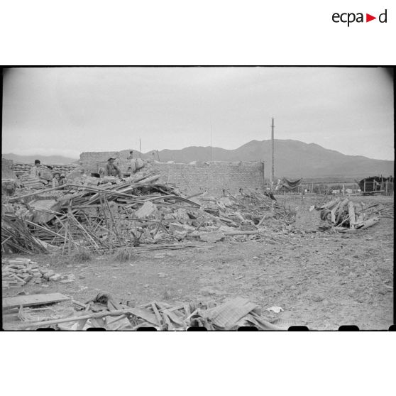 Des soldats fouillent les décombres d'un poste en ruines au Tonkin.