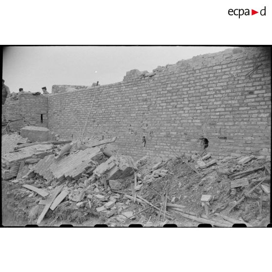Des soldats fouillent les décombres d'un poste en ruines au Tonkin.