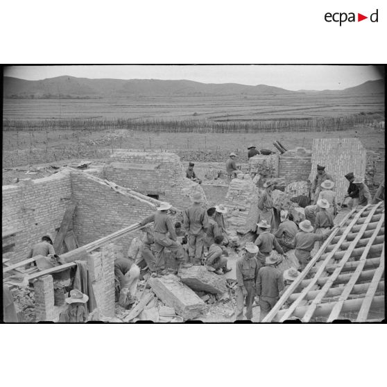 Des soldats fouillent les décombres d'un poste en ruines au Tonkin.