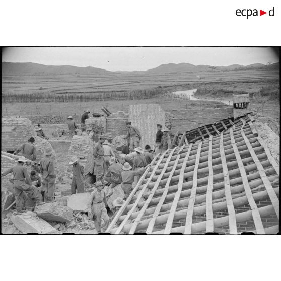 Des soldats fouillent les décombres d'un poste en ruines au Tonkin.