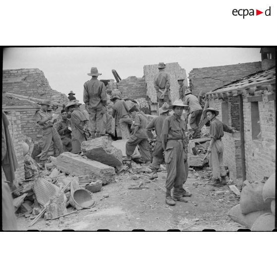 Des soldats fouillent les décombres d'un poste en ruines au Tonkin.