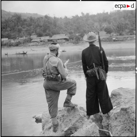 Un goumier du 17e tabor et un partisan observent le village de Chieng Nuoi situé sur le versant opposé de la rivière Nam Na.