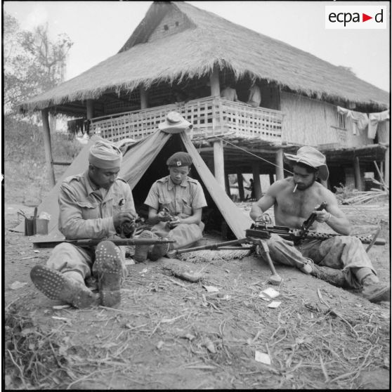 Préparation de l'armement avant de partir en opération par un goumier du 17e tabor, un partisan et un parachutiste.