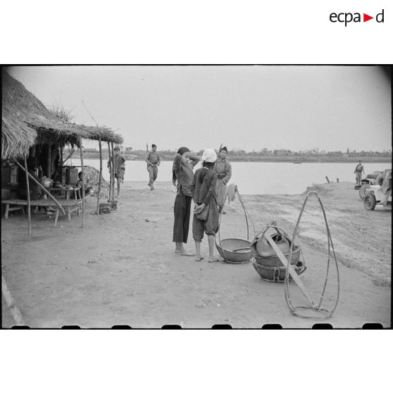 Deux jeunes filles ; en arrière plan, deux soldats armés.