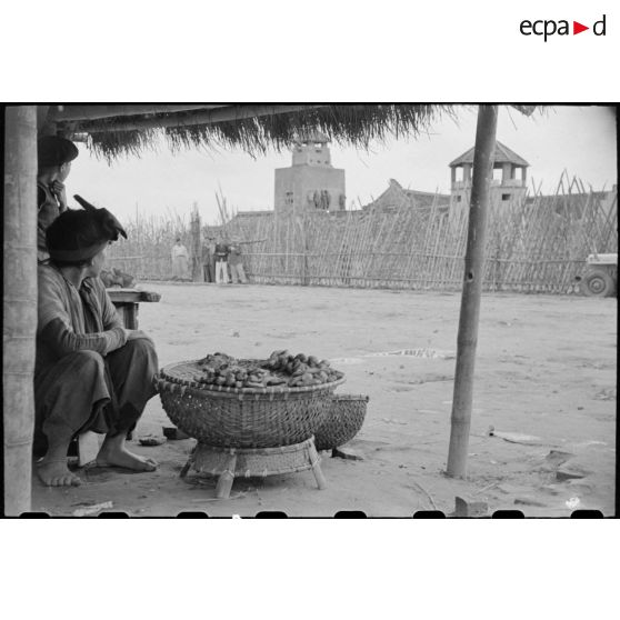 Scène de marché devant un poste.