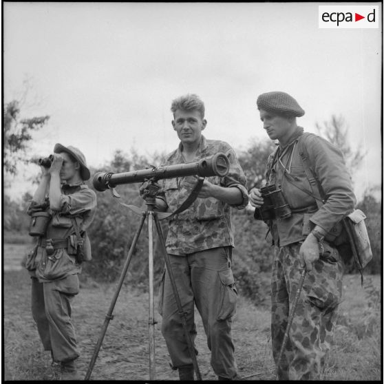 Observation aux jumelles avec au premier plan, un matériel optique monté sur trépied.