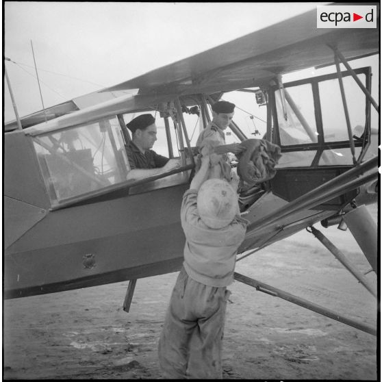 Chargement des sacs de courriers dans un avion Morane-Saulnier avant un départ en mission dans le delta du Tonkin.
