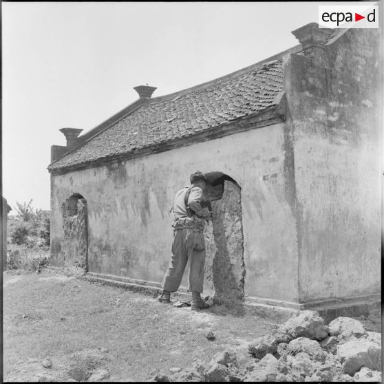 Un soldat observe l'intérieur d'une maison.
