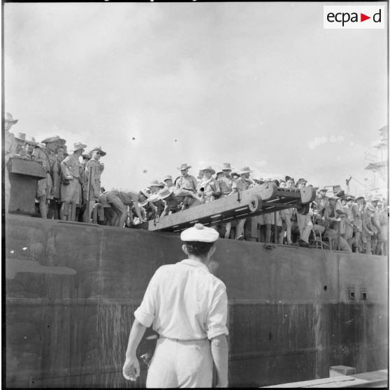 Mise en place de la passerelle. Au premier plan et de dos, un marin s' apprête à la recevoir.