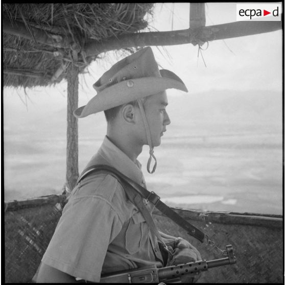 Un soldat, arme à l'épaule, fait le guet.