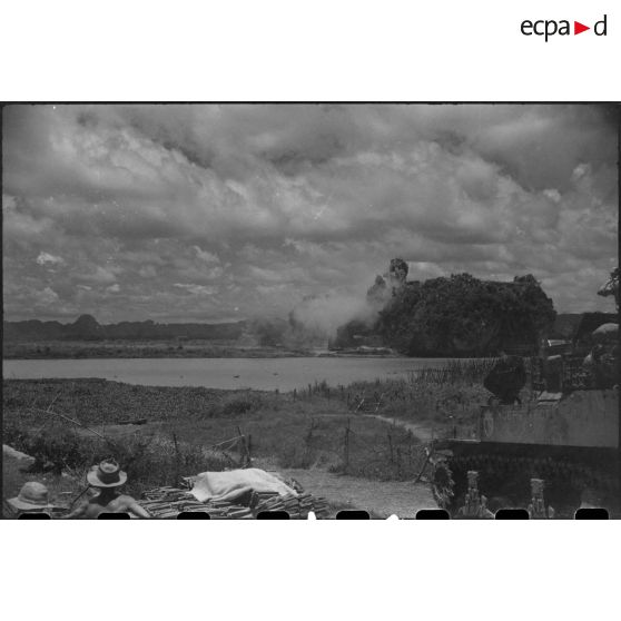 Tir d'un blindé sur un objectif au delà d'un plan d'eau.