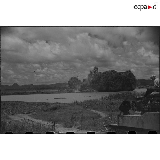 Tir d'un blindé sur un objectif au delà d'un plan d'eau.