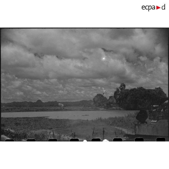 Tir d'un blindé sur un objectif au delà d'un plan d'eau.