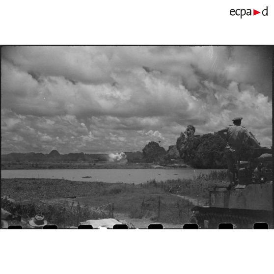 Tir d'un blindé sur un objectif au delà d'un plan d'eau.