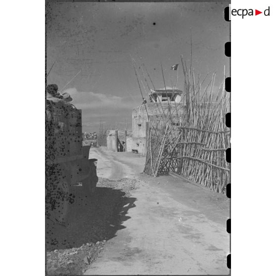 Passage des troupes en camion devant un poste fortifié.