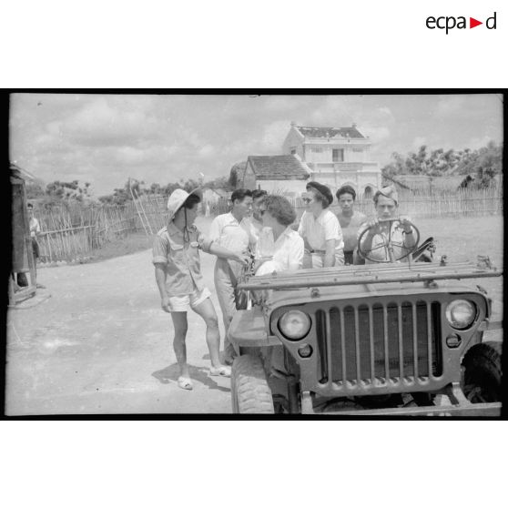 Les assistantes sociales à bord d'une jeep, discutent avec des vietnamiens.