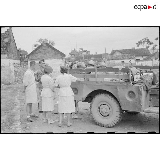 Personnel féminin et officier près d'un véhicule contenant des colis.
