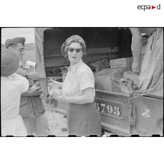 Personnel féminin et soldat devant le camion contenant les colis.