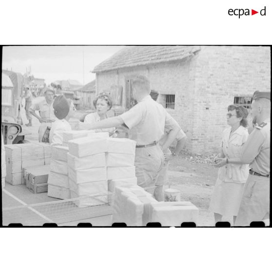 Officiers et personnel féminin autour des colis qui ont été empilés sur des tables.