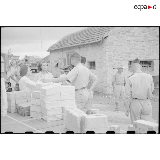Officiers et personnel féminin autour des colis qui ont été empilés sur des tables.