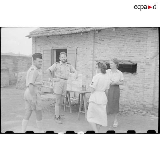 Officiers et personnel féminin autour des colis qui ont été empilés sur des tables.