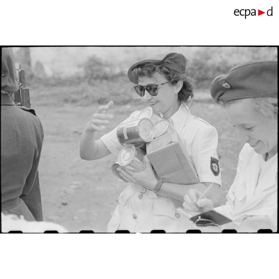 Déchargement de colis et boites de conserve par le personnel féminin.