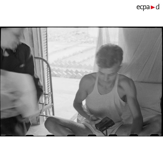 Un soldat, assis sur son lit, reçoit un paquet.