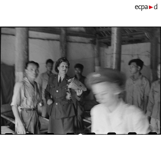 Personnel féminin tenant un colis et entouré de soldats vietnamiens.