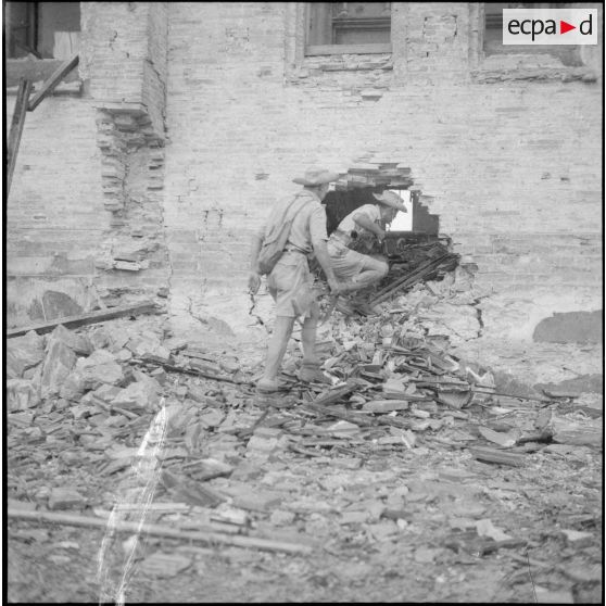 Deux tirailleurs algériens pénétrant dans une maison en ruine.