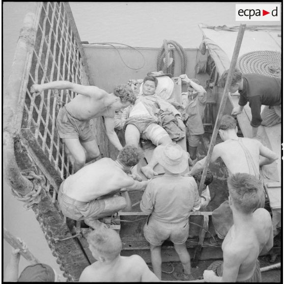 A l'aide de civières, les soldats évacuent des blessés viêt-minhs qu'ils transportent à bord du Landing Ship Support Large (LSSL).