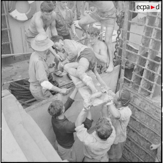 A l'aide de civières, les soldats évacuent des blessés viêt-minhs qu'ils transportent à bord du Landing Ship Support Large (LSSL).