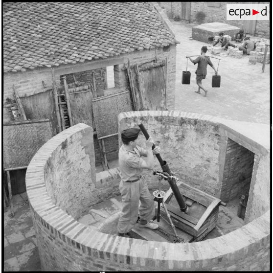 Poste de Thaï Dao : nettoyage d'un mortier Brandt de 81 mm M-27/31 installé à l'intérieur d'un petit mur circulaire.