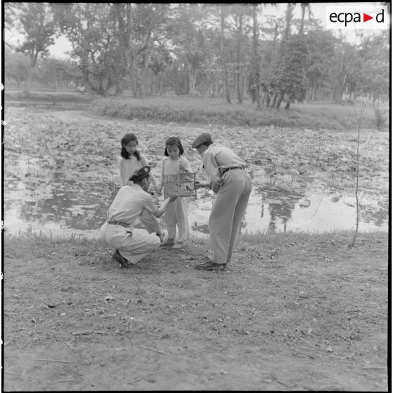 Militaires français du 6e bataillon de parachutistes coloniaux rencontrant des enfants, dans un parc de Hanoï.