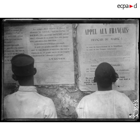 Casablanca. Maroc. Indigènes lisant les affiches rédigées en français et en arabe et relatant les victoirese des alliés. [légende d'origine]