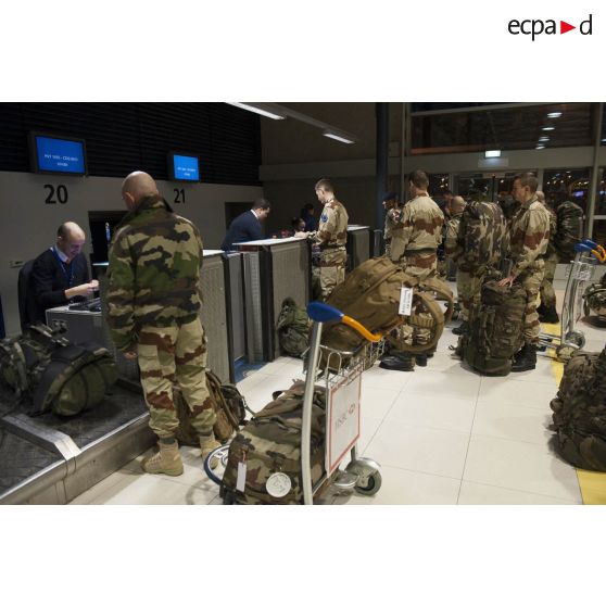 Des instructeurs européens enregistrent leurs bagages au guichet d'embarquement à l'aéroport de Roissy-Charles-de-Gaulle.