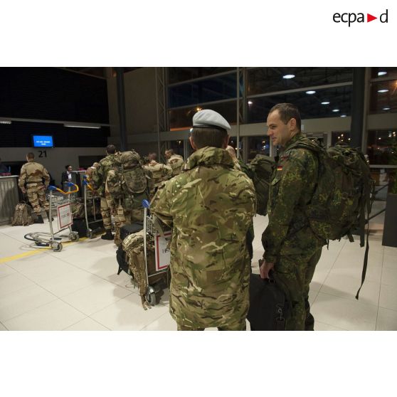 Des instructeurs allemands et britanniques discutent en attendant d'enregistrer leurs bagages au guichet d'embarquement à l'aéroport de Roissy-Charles-de-Gaulle.
