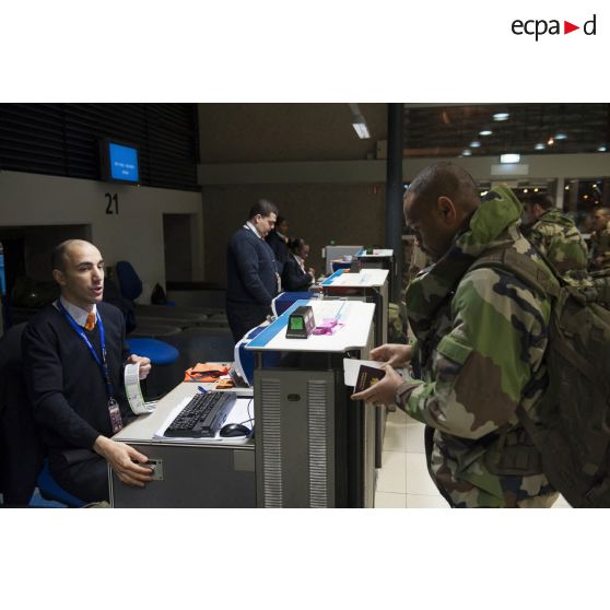 Un instructeur français enregistre ses bagages au guichet d'embarquement à l'aéroport de Roissy-Charles-de-Gaulle.