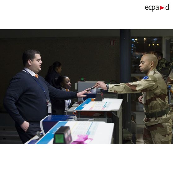 Un instructeur français enregistre ses bagages au guichet d'embarquement à l'aéroport de Roissy-Charles-de-Gaulle.