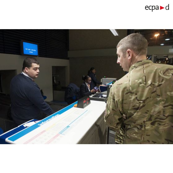 Un instructeur britannique enregistre ses bagages au guichet d'embarquement à l'aéroport de Roissy-Charles-de-Gaulle.