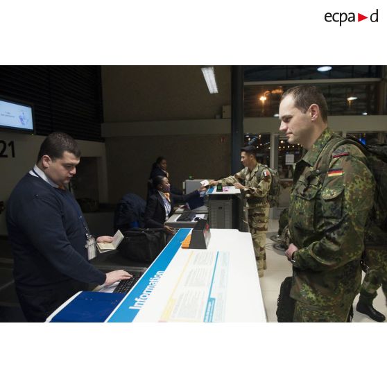 Un instructeur allemand enregistre ses bagages au guichet d'embarquement à l'aéroport de Roissy-Charles-de-Gaulle.