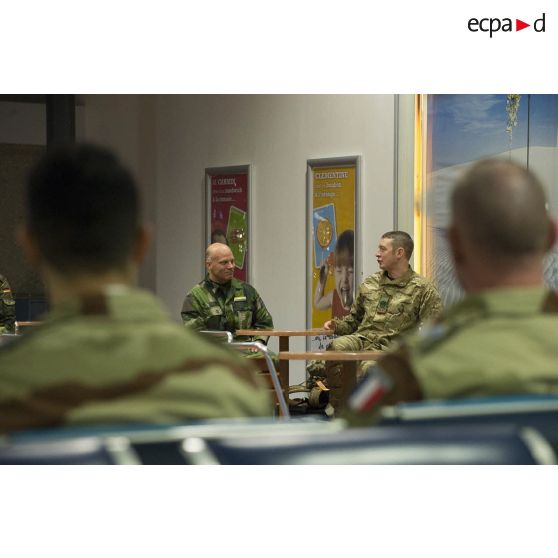 Un instructeur britannique discute avec son homologue letton dans une cafétéria de l'aéroport de Roissy-Charles-de-Gaulle.