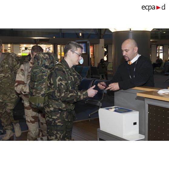 Un instructeur enregistre son billet au guichet d'embarquement à l'aéroport de Roissy-Charles-de-Gaulle.