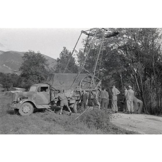 Dépannage d'une voiture par une grue Kfz-Aufsetzkran 3t installée sur un camion Opel Blitz.