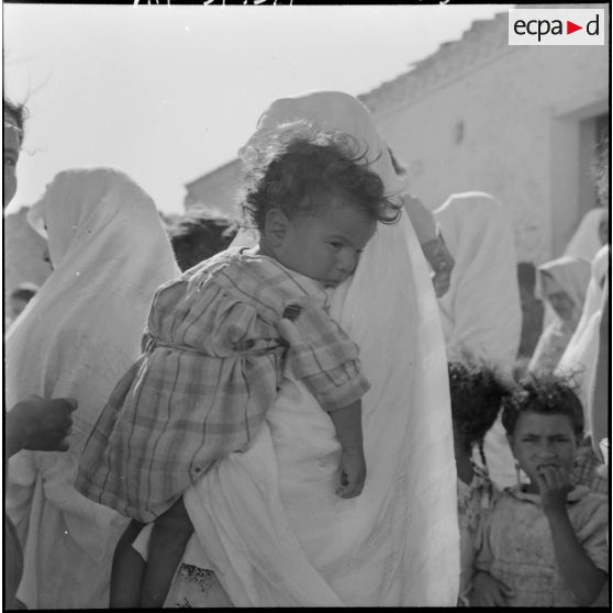 Portrait d'une femme qui tient son enfant dans ses bras pendant l'intervention d'une équipe médico-sociale itinérante (EMSI), dans un douar d'Oran.