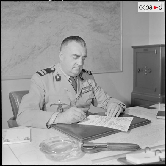 Portrait de trois-quarts gauche du colonel de gendarmerie Bezanger qui travaille assis à son bureau.